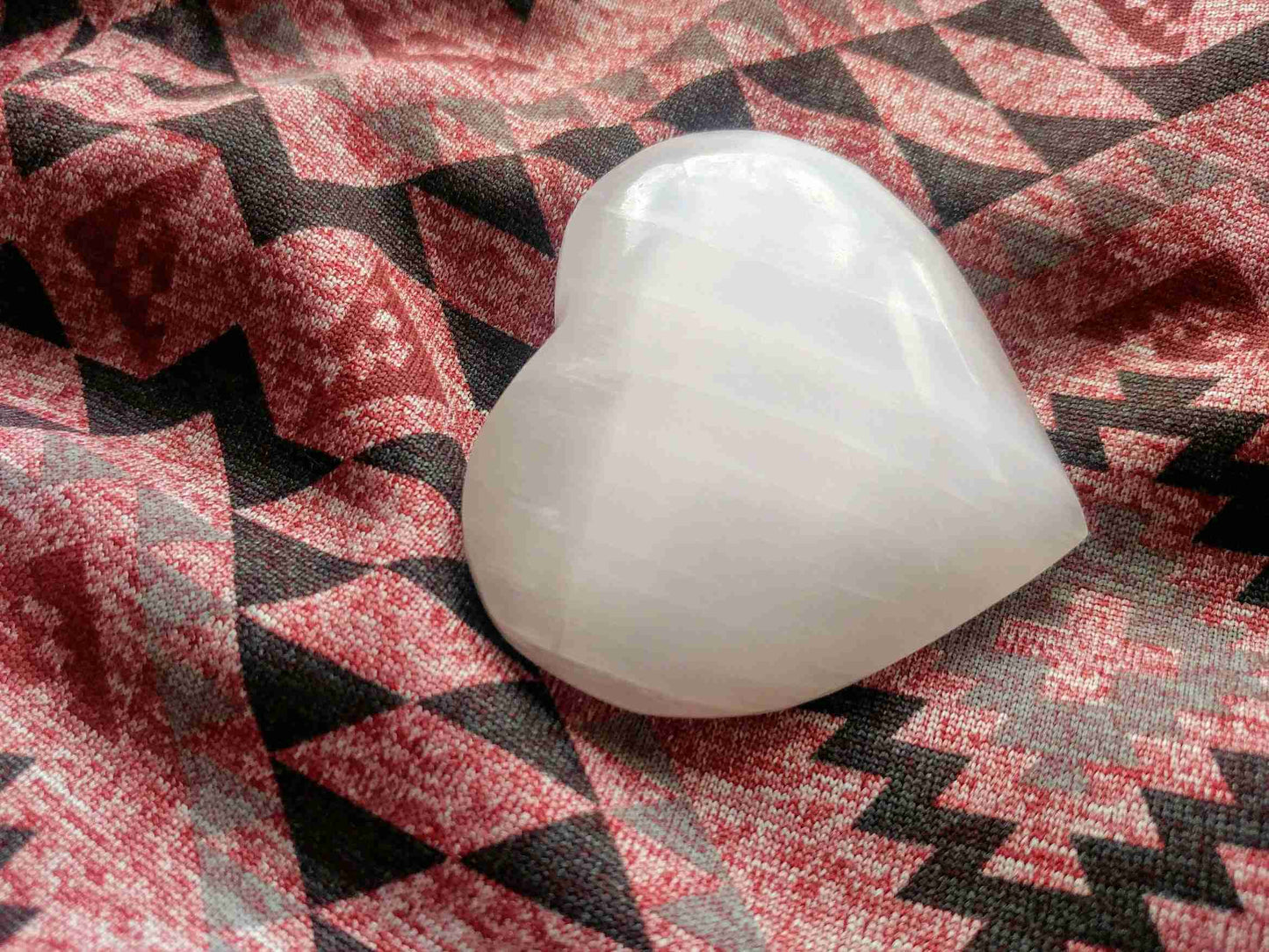 White Selenite Puffy Heart – Reiki Healing Crystal & Energy Cleanser displayed on patterned fabric. Ideal for meditation and energy work.