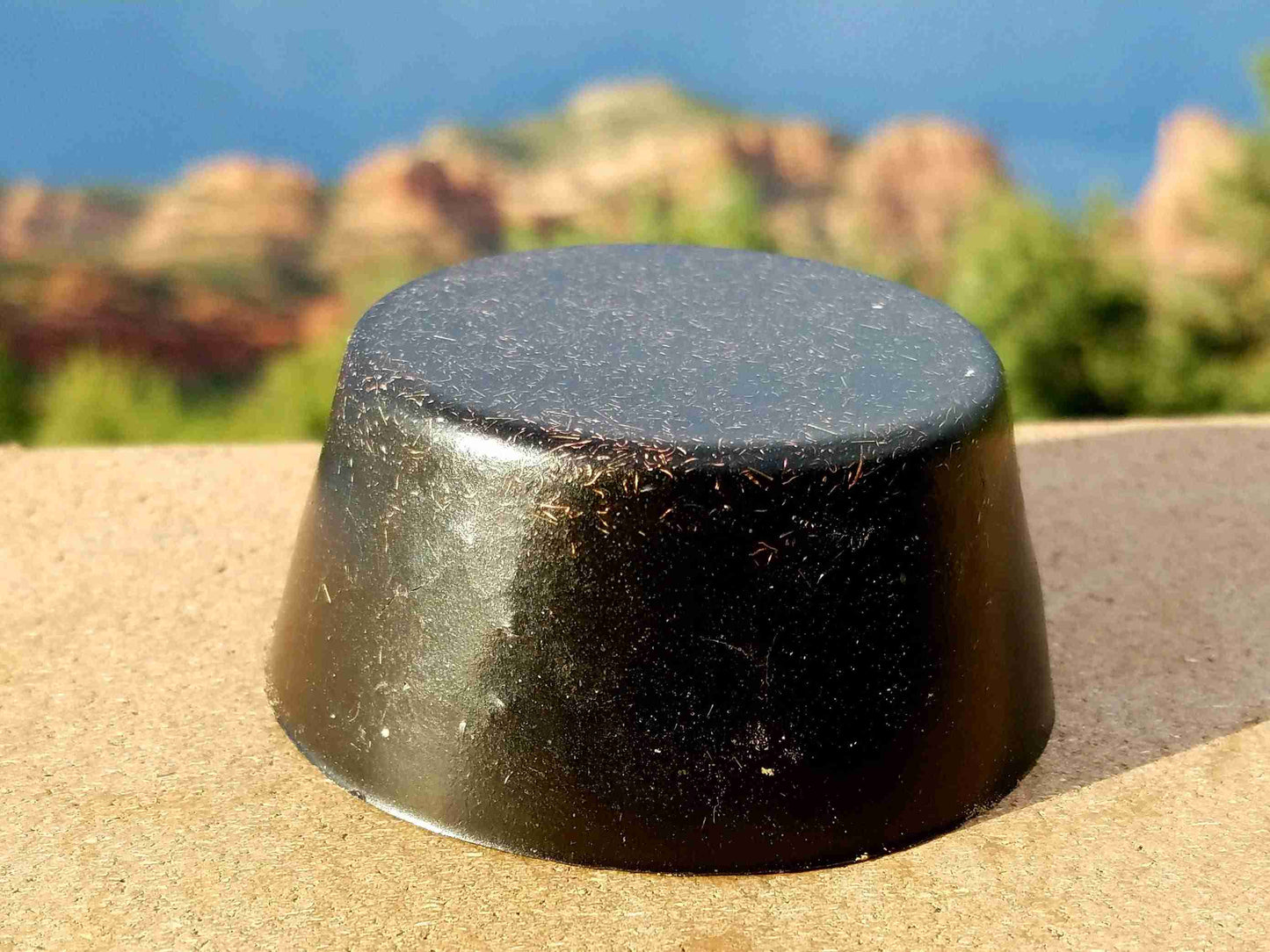Three black sun Orgonite tower busters with a scenic background of a landscape with red mountains. orgone generator pyramid black sun