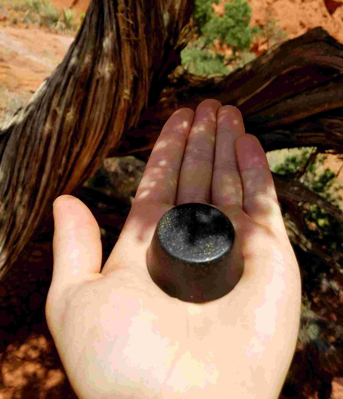 Black Sun Orgonite® Tower Buster in hand, showcasing its smooth surface and orgone energy generator design.