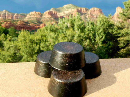 Three black sun Orgonite tower busters with a scenic background of a landscape with red mountains. orgone generator pyramid black sun
