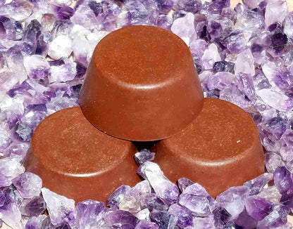 Three brown Orgonite Tower Busters with a mix of red and clear quartz, rose, amethyst, black tourmaline, and red jasper gemstones, placed on a bed of purple crystals.