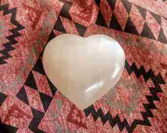 White Selenite Puffy Heart – Reiki Healing Crystal & Energy Cleanser displayed on patterned fabric. Ideal for meditation and spiritual healing.